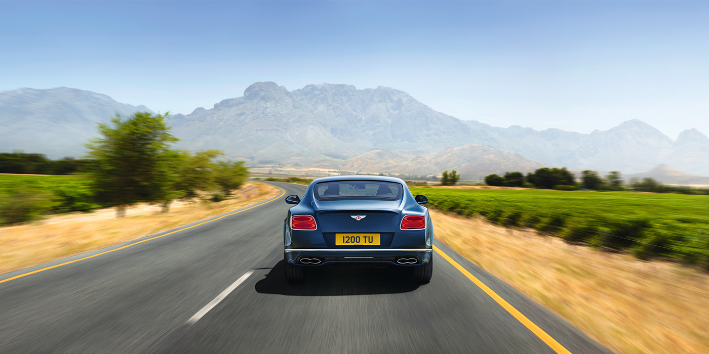 Gohm Sportwagen GmbH | Bentley Stuttgart Bentley Pre Owned Bentley Continental GT in Marlin blue paint seen from rear on country road