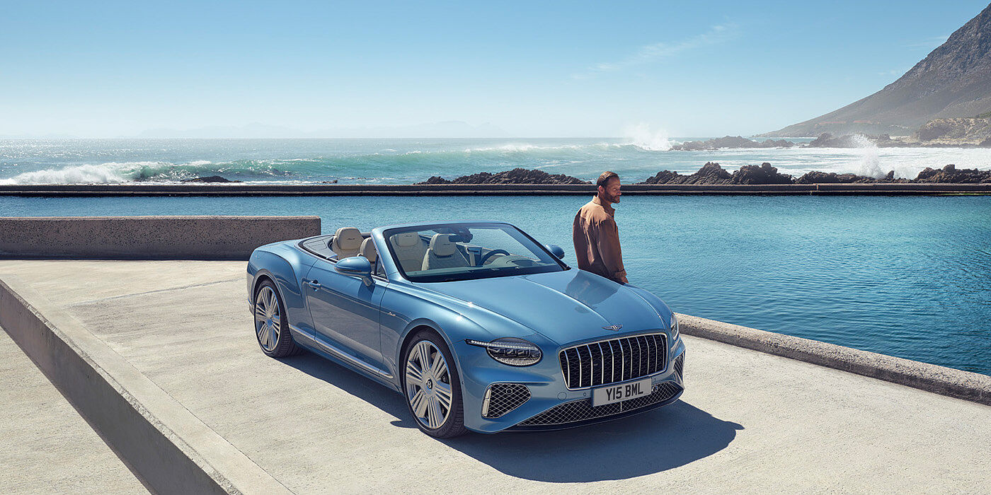 Gohm Sportwagen GmbH | Bentley Stuttgart New Bentley Continental GTC Azure convertible front view in Light Windsor blue paint with 22 inch ten spoke wheels parked by the sea in the sunshine
