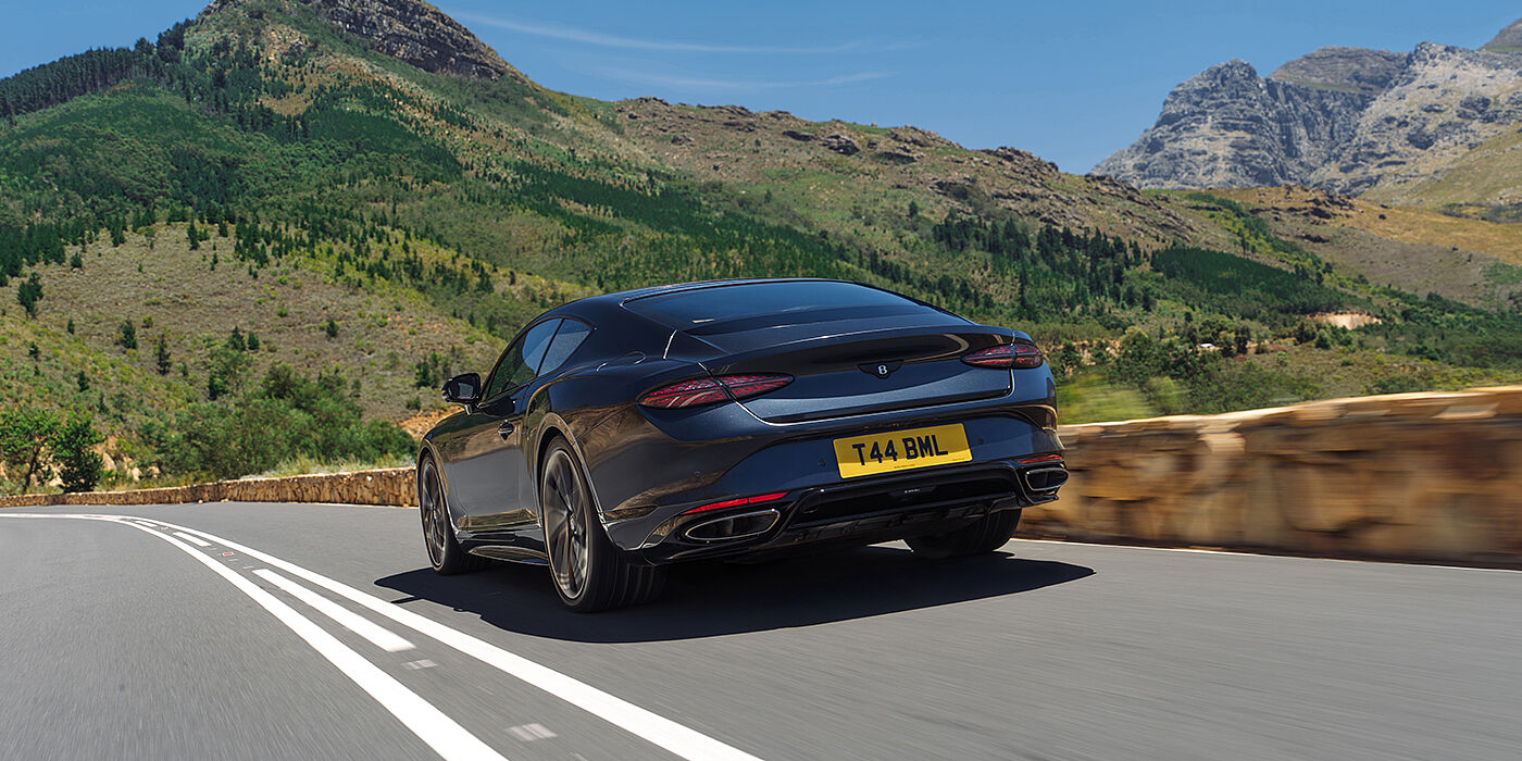 Gohm Sportwagen GmbH | Bentley Stuttgart Bentley Continental GT coupe in Thunder paint rear driving through mountains in sunshine