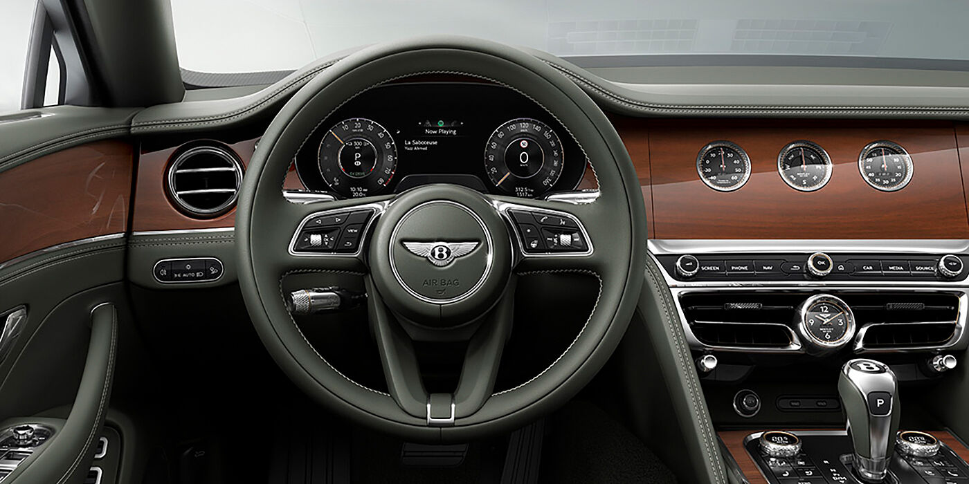 Gohm Sportwagen GmbH | Bentley Stuttgart New Bentley Flying Spur sedan front cabin in Cumbrian Green hide and Crown Cut walnut veneer showing steering wheel and Rotating Display with three clocks on face