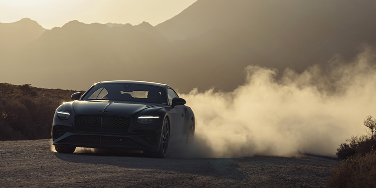 Gohm Sportwagen GmbH | Bentley Stuttgart Bentley Continental GT coupe in Thunder paint front 3/4 driving with dust trail at sunset