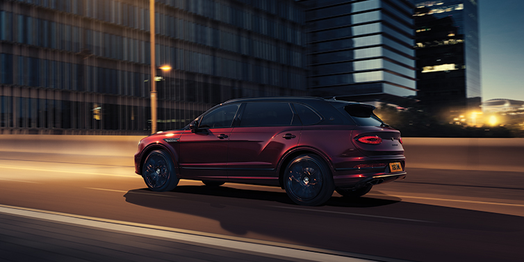 Gohm Sportwagen GmbH | Bentley Stuttgart Bentley Bentayga Extended Wheelbase Mulliner SUV in Cricket Ball red paint driving dynamically in city at night